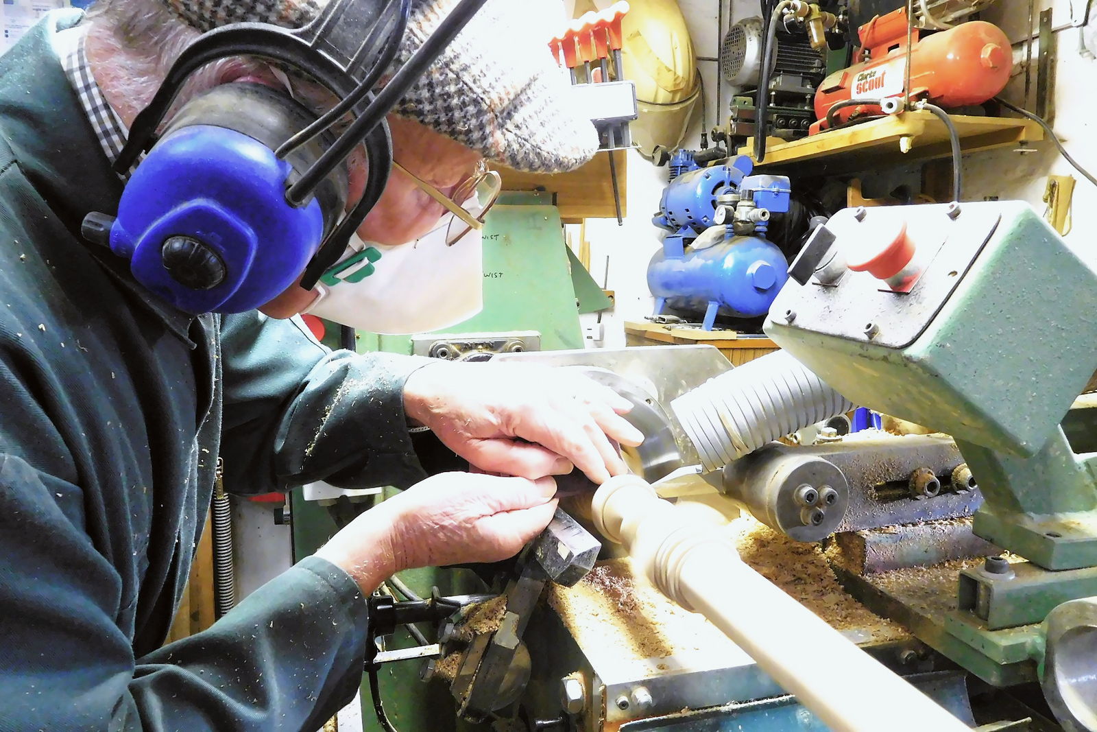 A maker hand-sanding a turned spindle at the bench