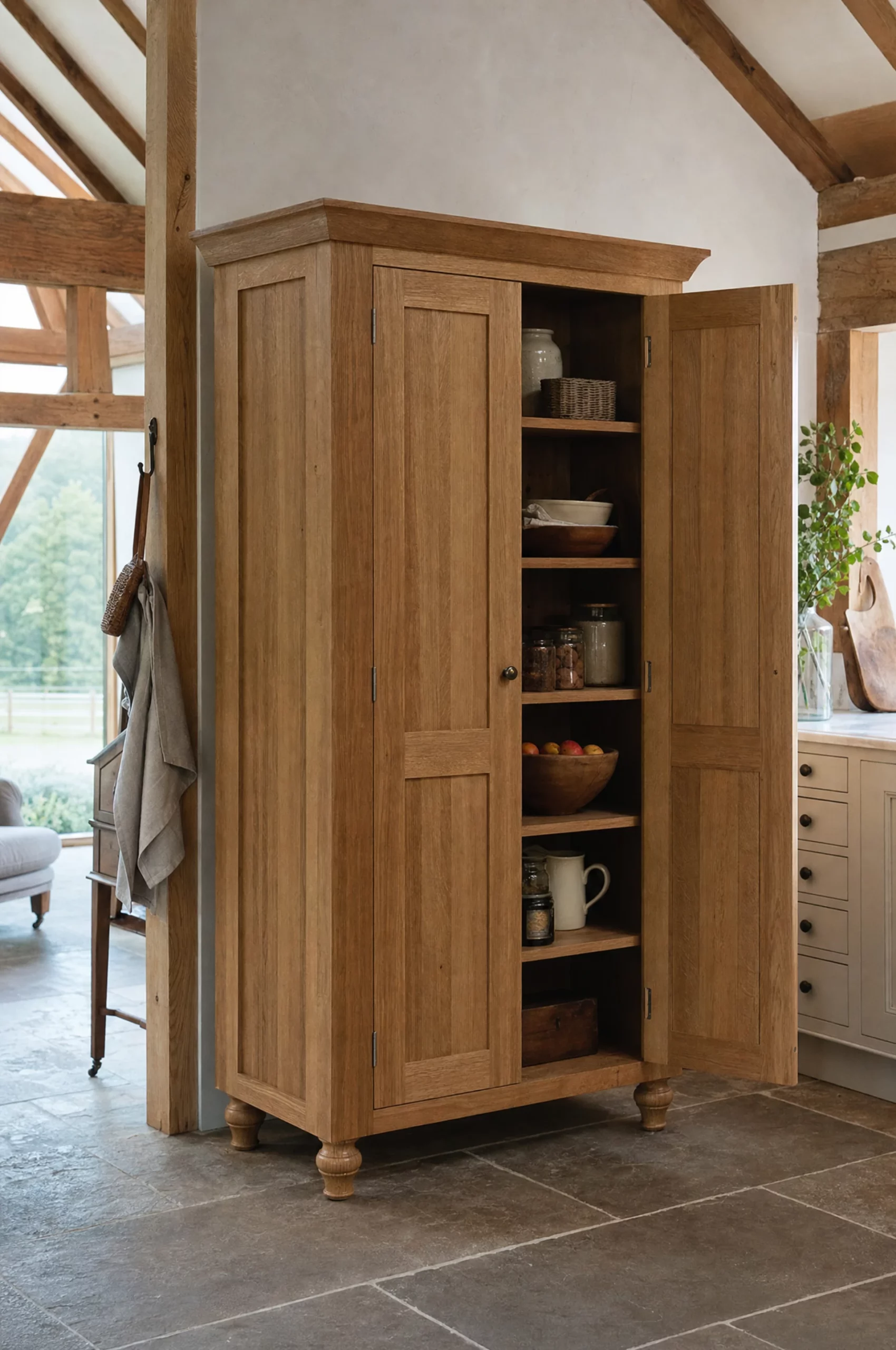 A tall oak larder cupboard standing open, shelves and jars inside