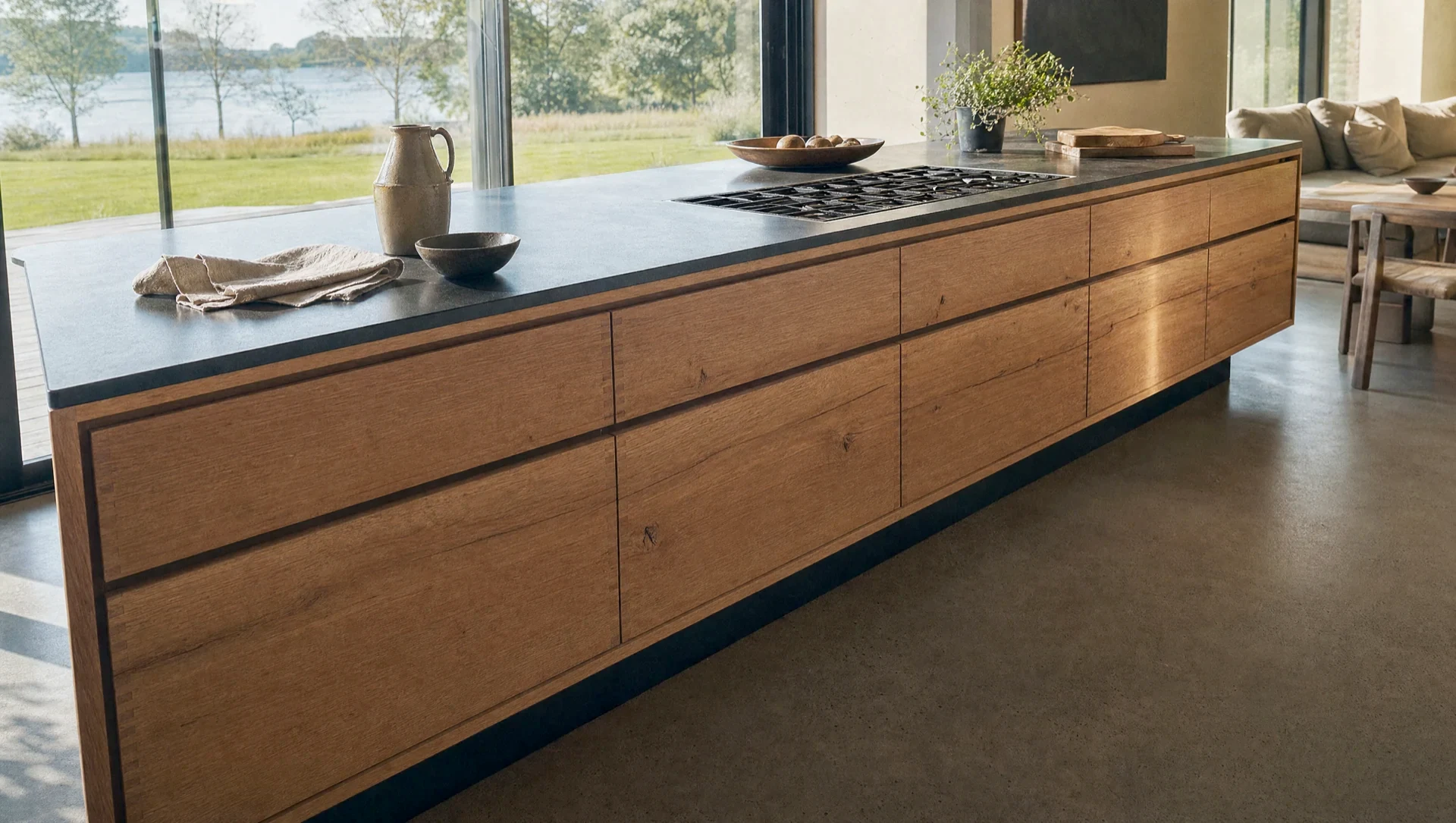 The island straight on, the cooktop set flush into the dark top over handleless oak fronts