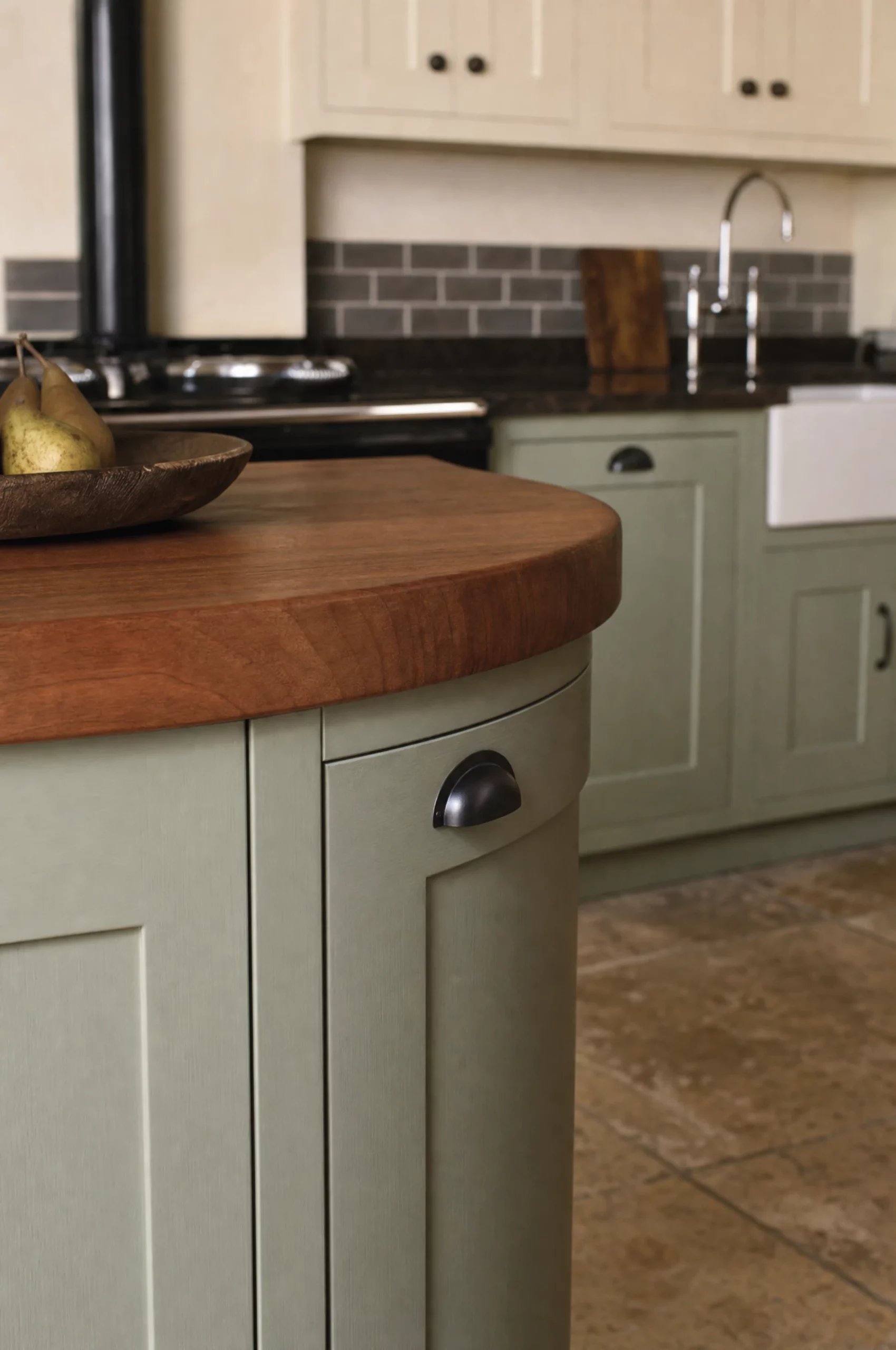 The walnut top meeting the dark stone of the run, with the cooktop and the sink beyond